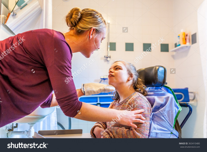 stock-photo-disabled-child-in-a-wheelchair-being-cared-for-by-a-special-needs-nurse-working-with-disability-363410480